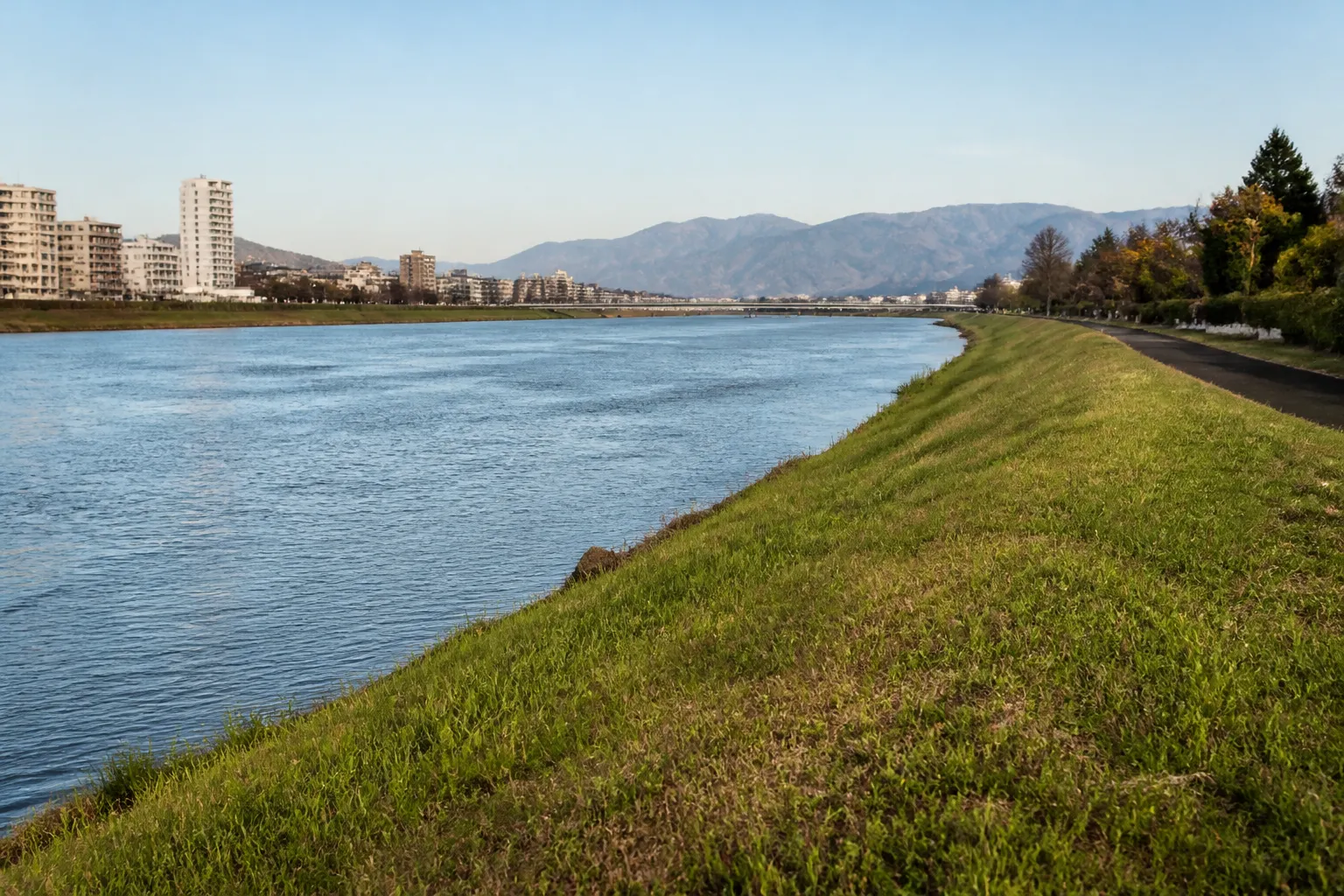 Digue enherbée longeant une rivière en zone urbaine