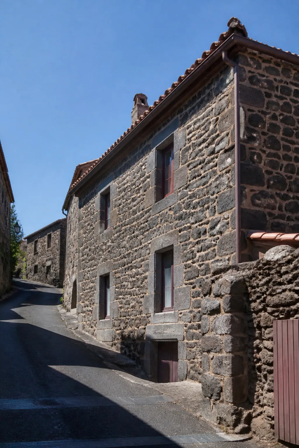 Façade en pierre volcanique sombre d’une maison de bourg en Haute-Loire