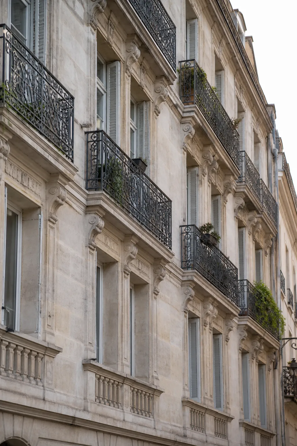 Immeuble ancien en pierre claire avec balcons en fer forgé