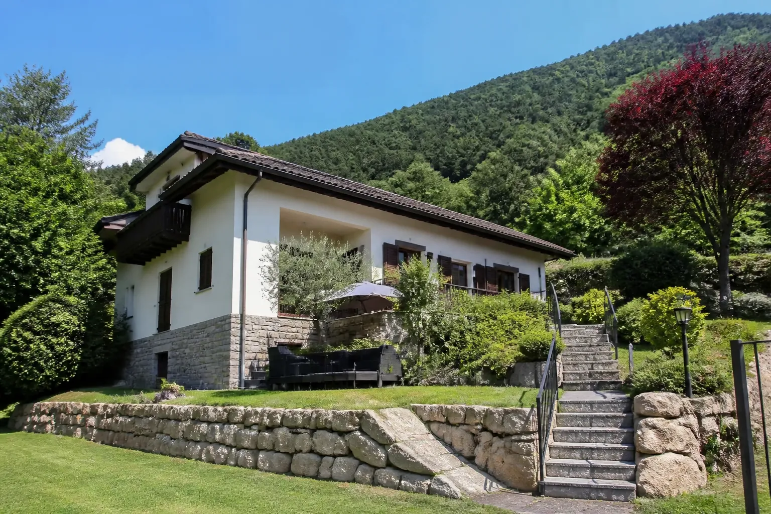 Maison individuelle construite sur un terrain en pente avec mur de soutènement