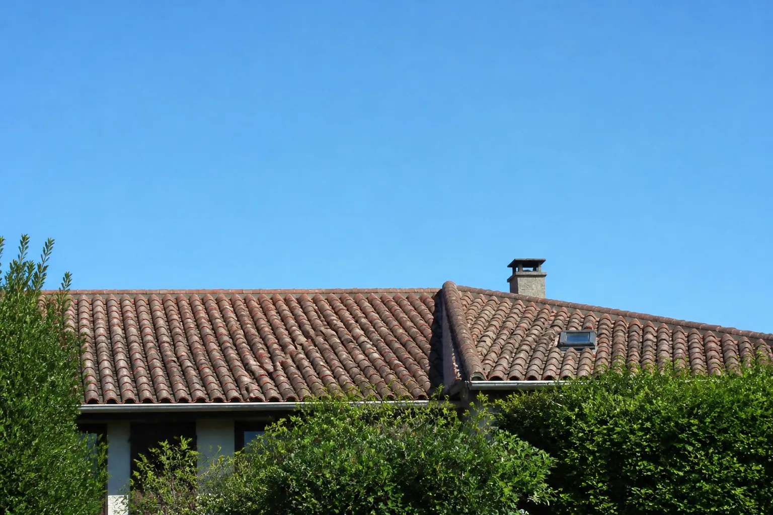Toiture en tuiles canal d’une maison vue depuis le jardin