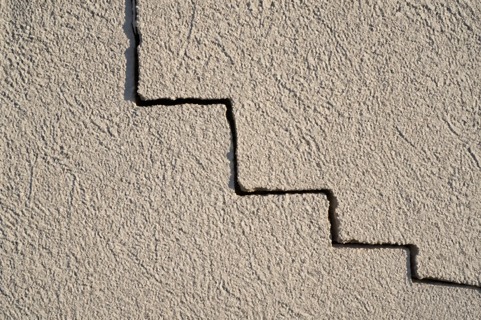 Fissure en escalier sur un mur de brique enduit