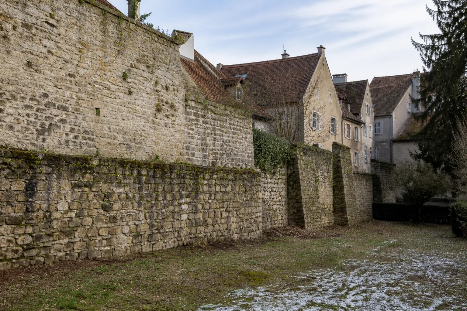Rempart en pierre ancien bordant des maisons