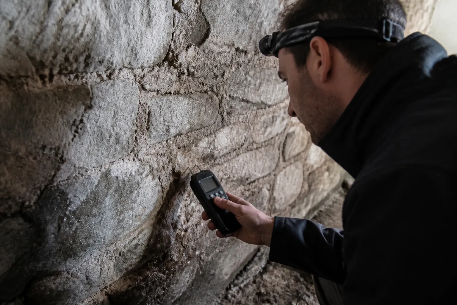 Expert mesurant l’humidité d’un mur de cave en pierre