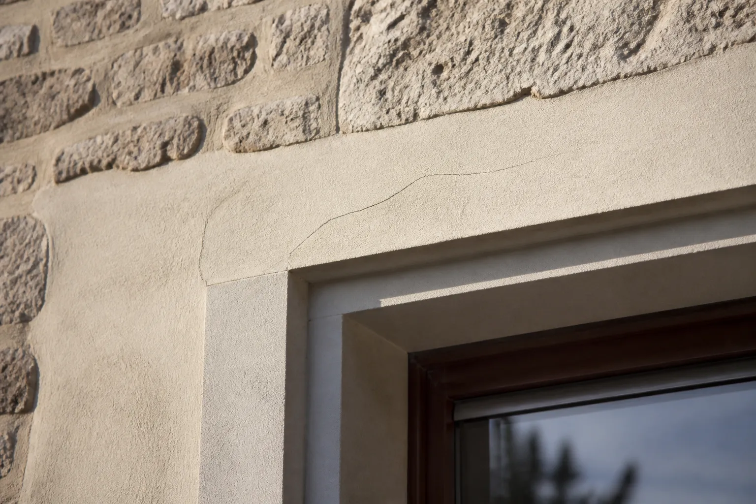 Façade en pierre avec une fissure fine au-dessus d’une fenêtre