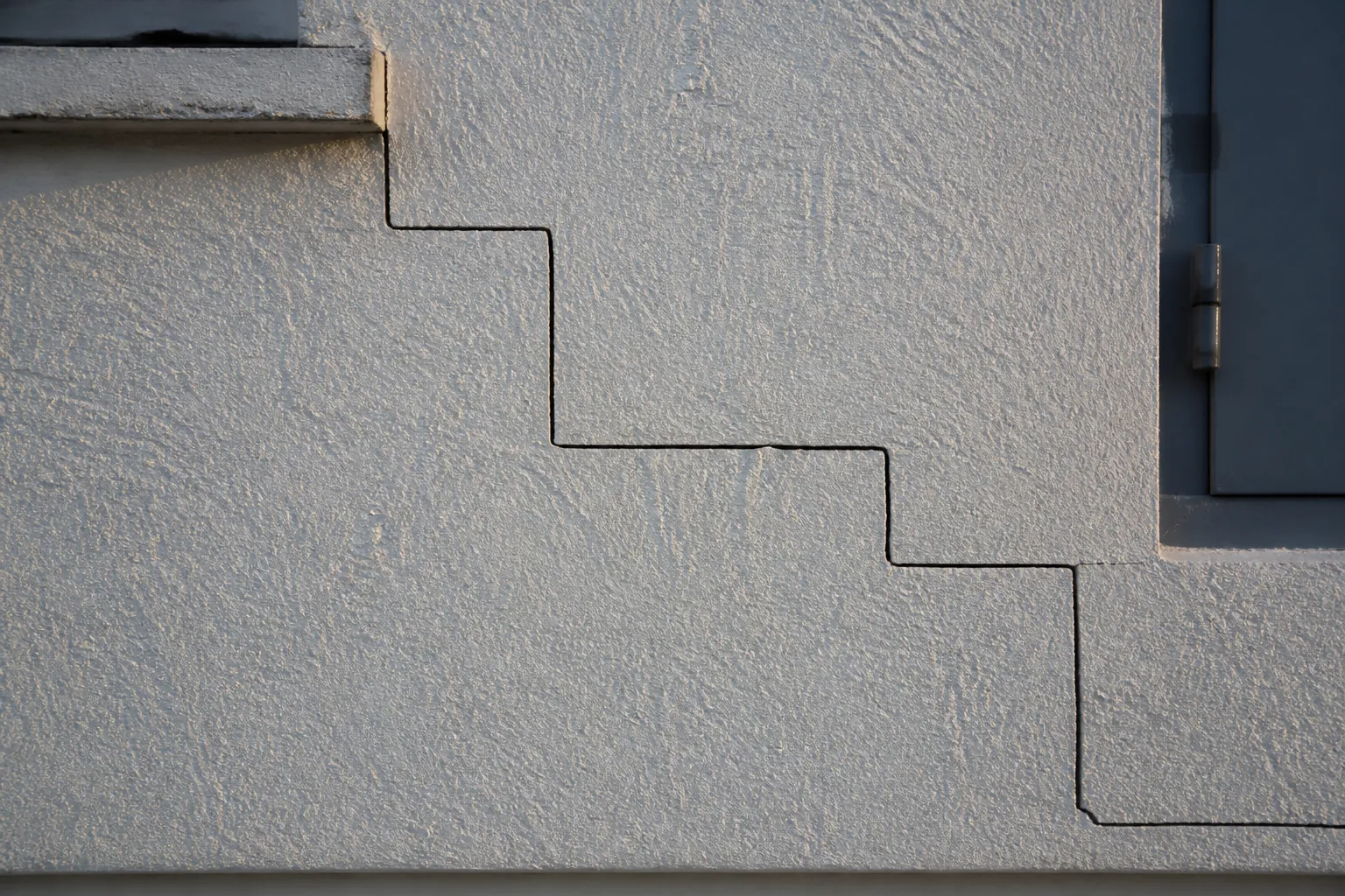 Fissure en escalier sur un mur de maison en briques enduites