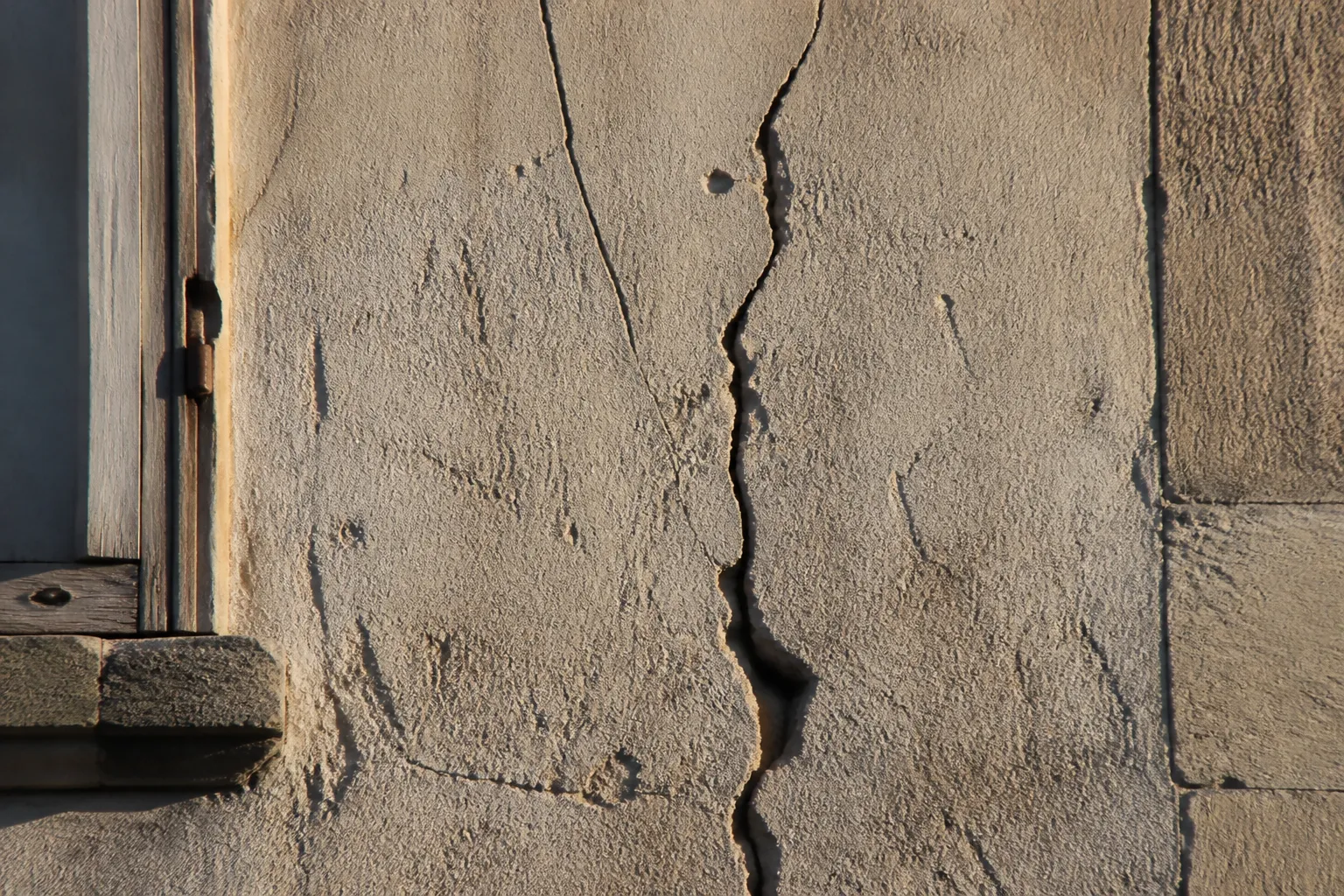 Fissure verticale sur une façade enduite