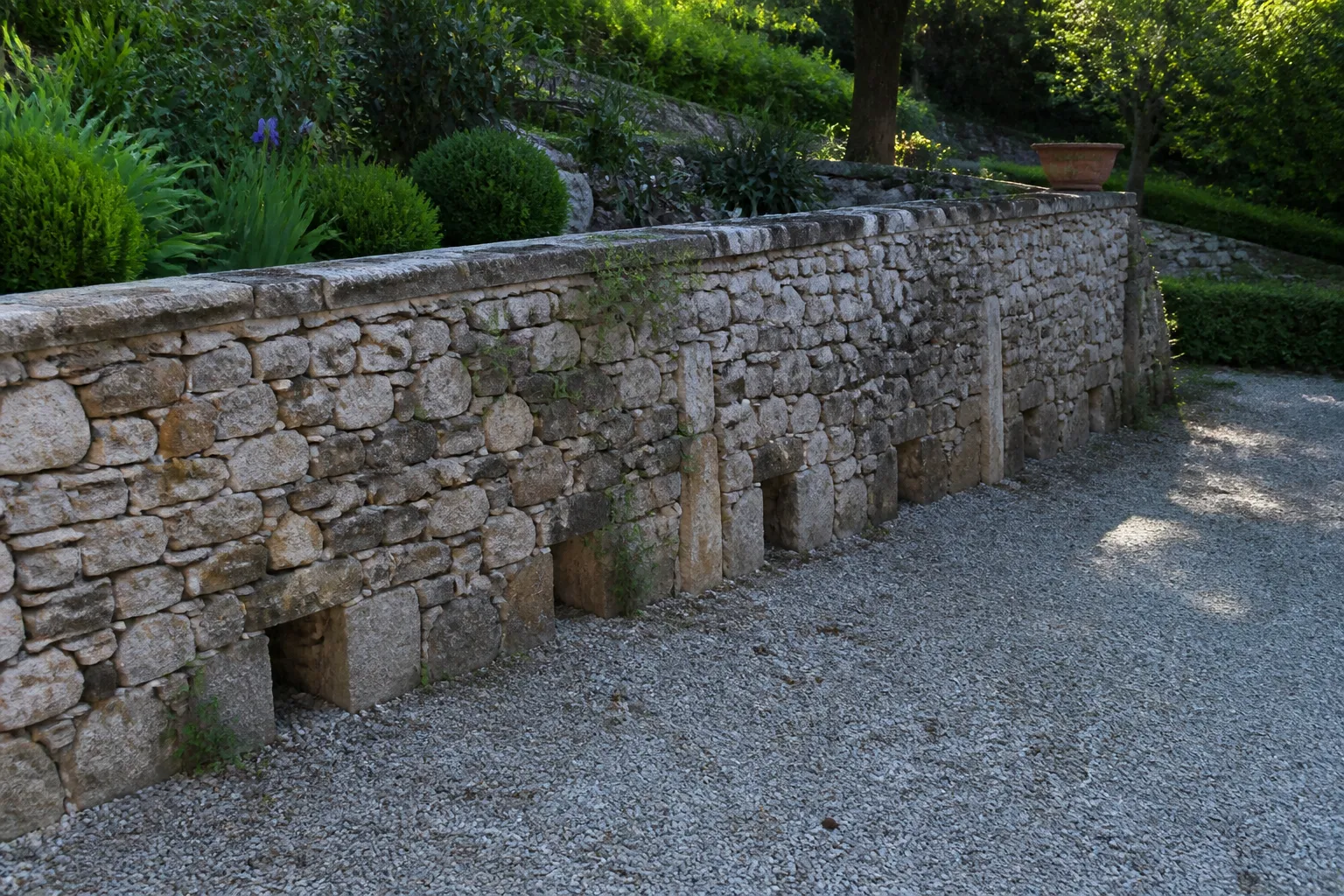 Mur de soutènement en pierre dans un jardin en pente