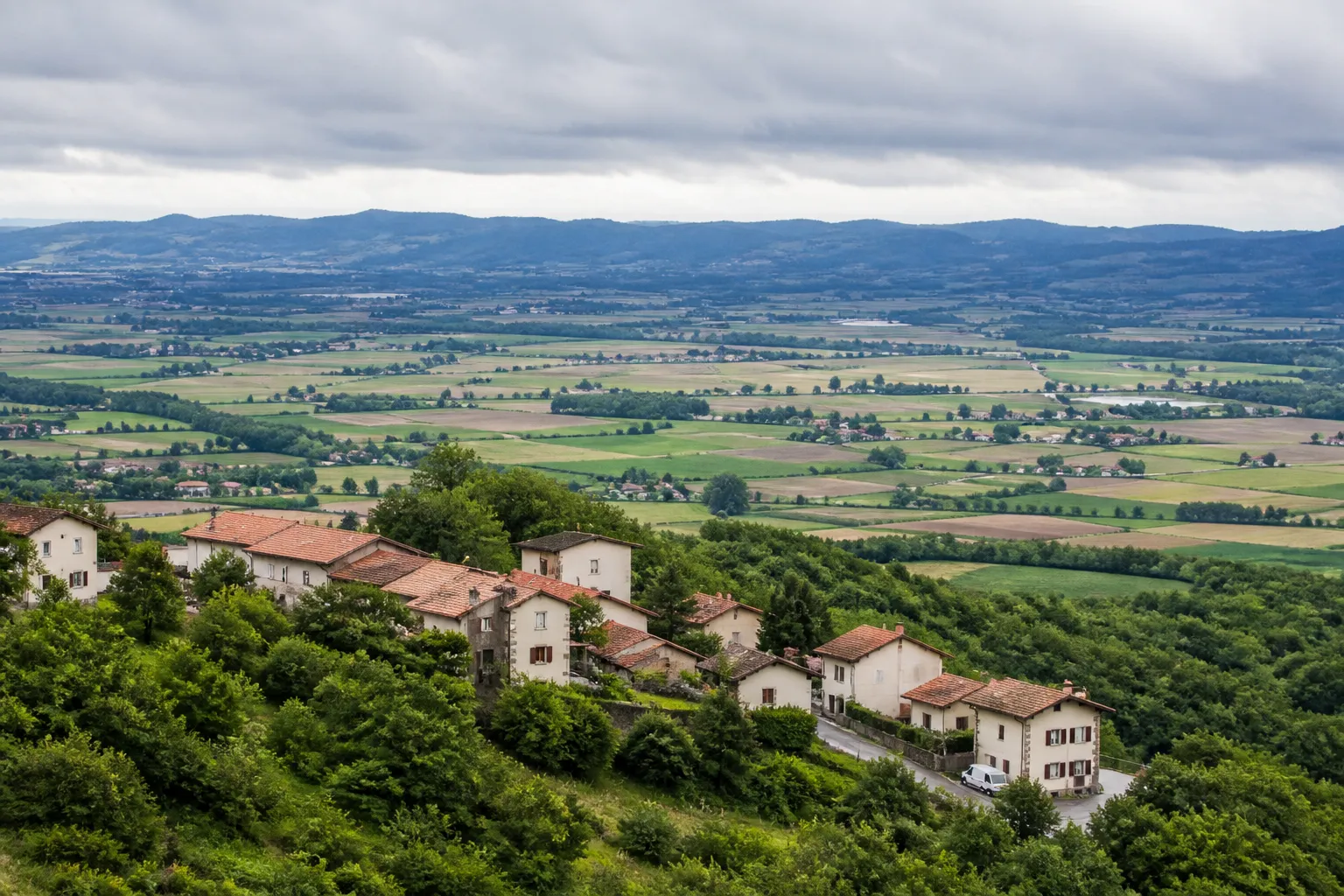 Village de piémont avec maisons sur un versant et plaine en contrebas