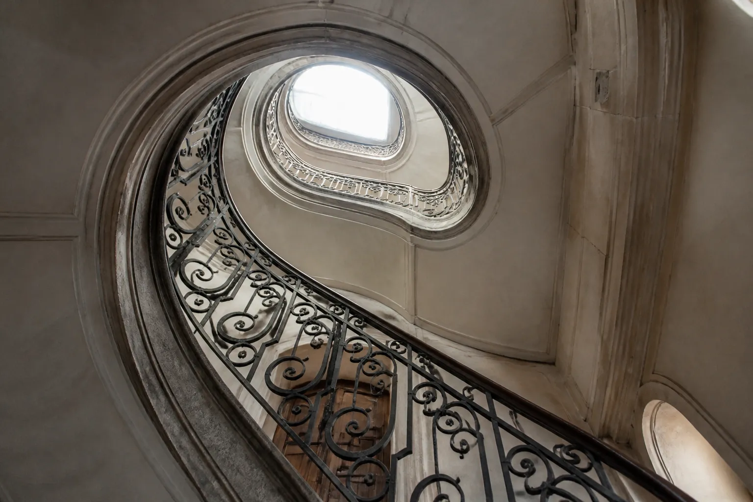 Cage d’escalier d’un immeuble ancien avec rampe en fer forgé