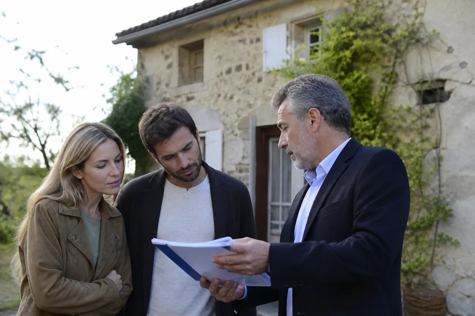 Acheteurs discutant avec un expert devant une maison