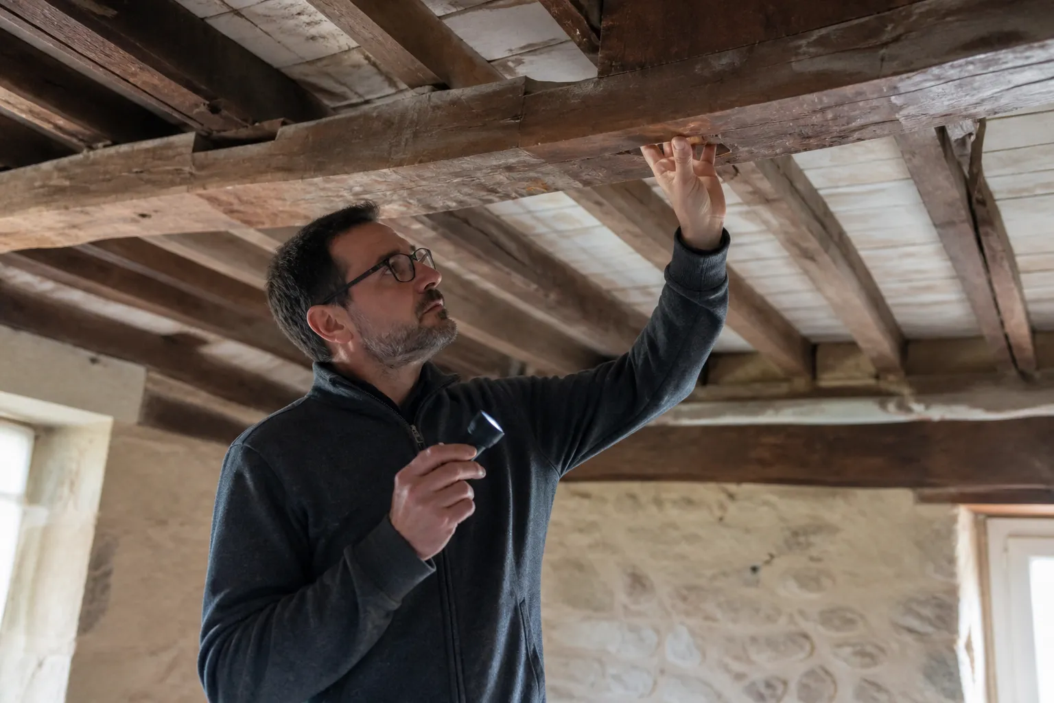Expert examinant les poutres d’un plafond ancien