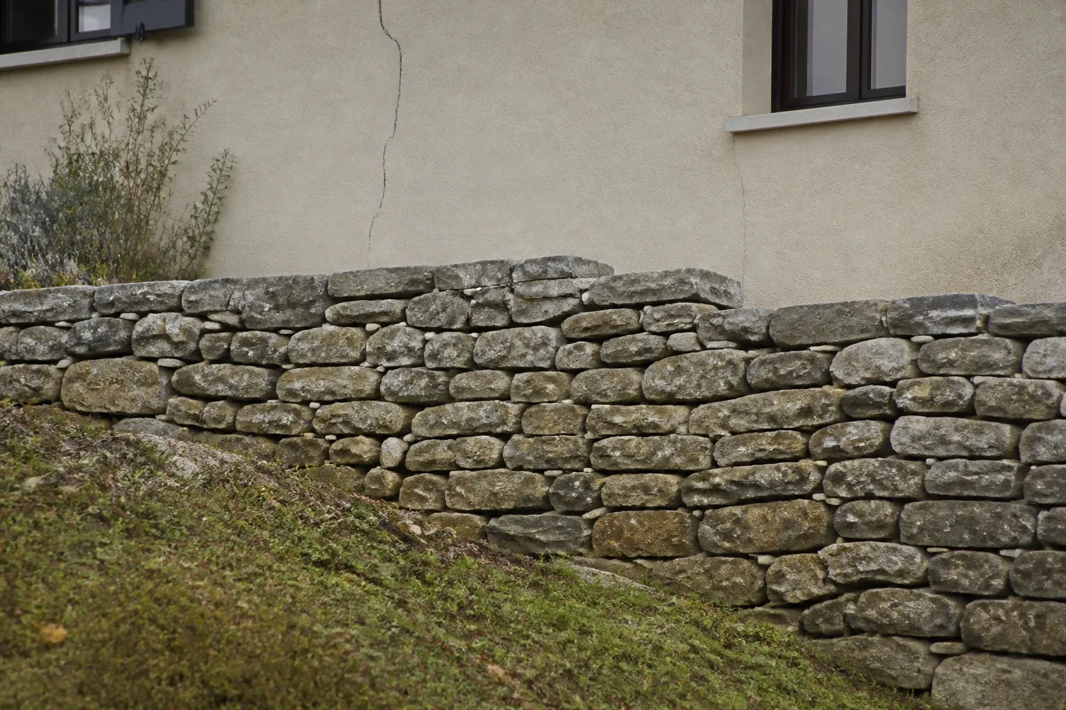 Mur de soutènement en pierre au pied d’une maison construite sur un terrain en pente