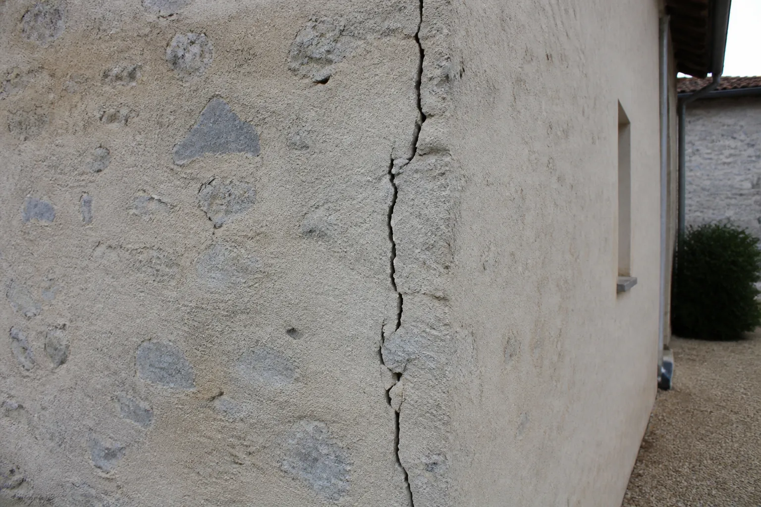 Fissure verticale sur un mur de maison en moellons enduits