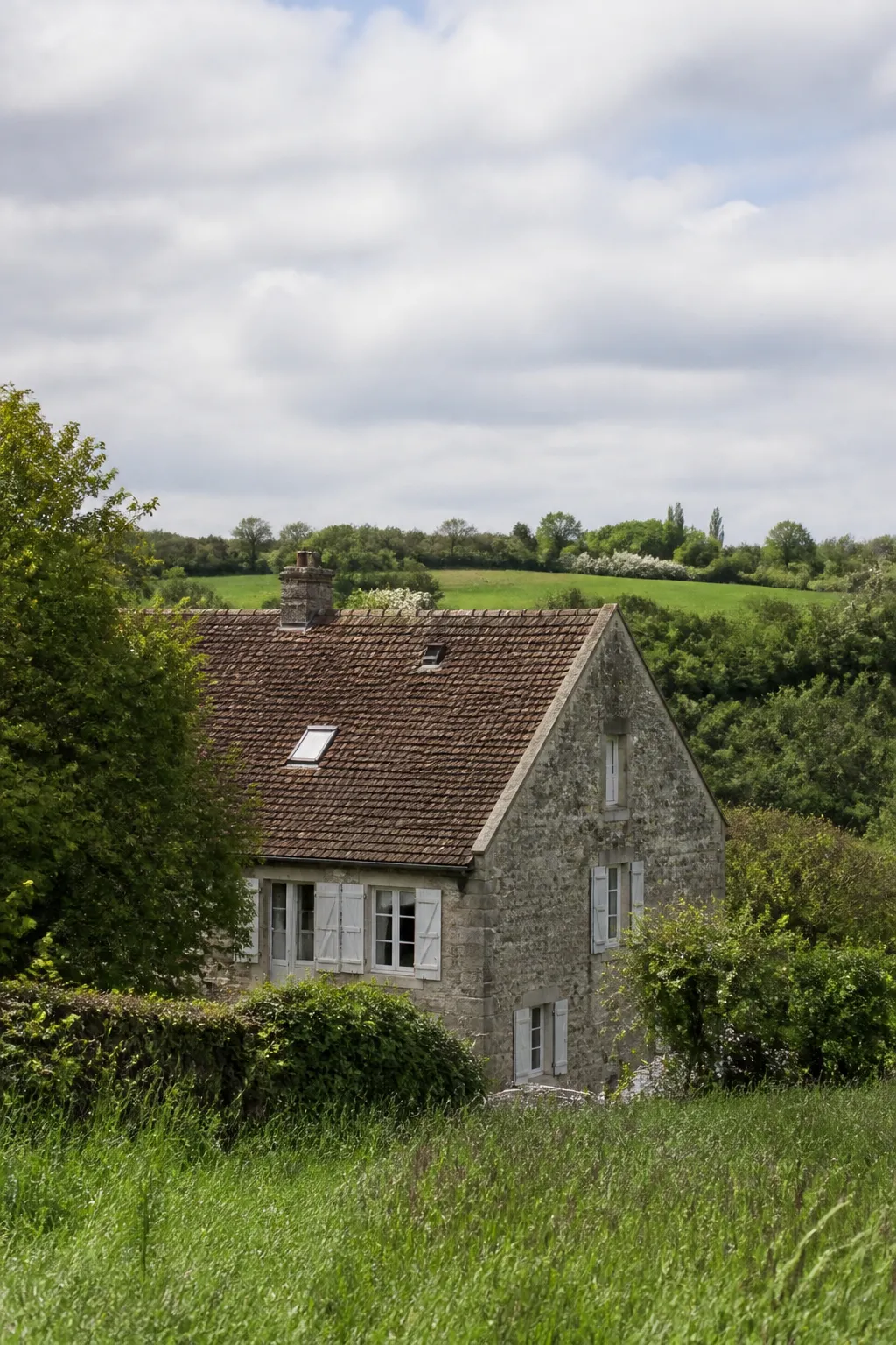 Maison en pierre grise au milieu de prairies bocagères