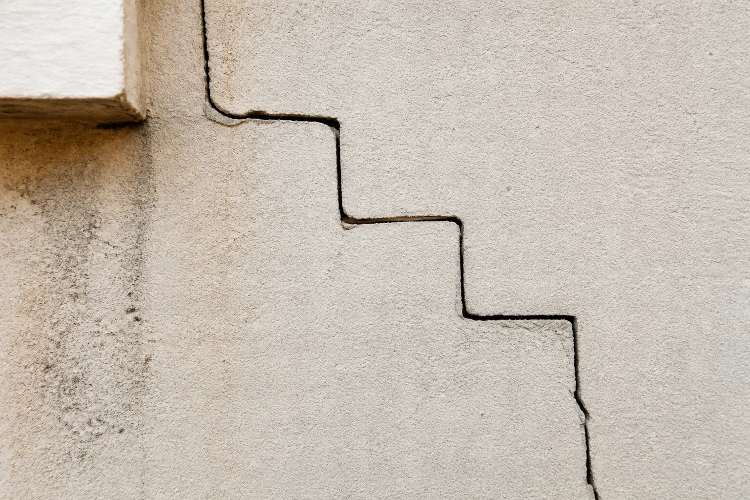 Fissure en escalier sur un mur extérieur enduit