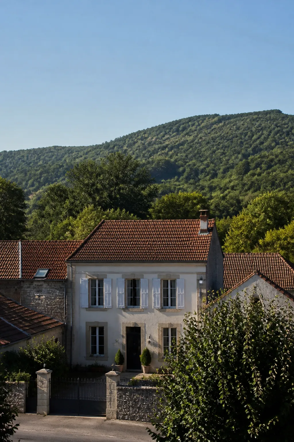 Maison de ville en pierre et enduit au pied de collines boisées, examinée avant achat