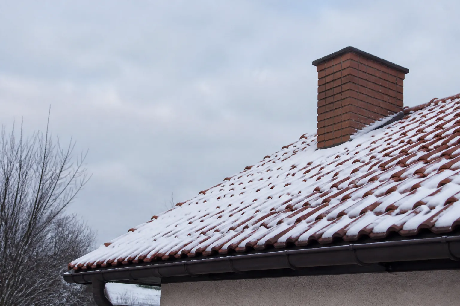 Toiture de tuiles enneigée d’une maison de l’est de la France