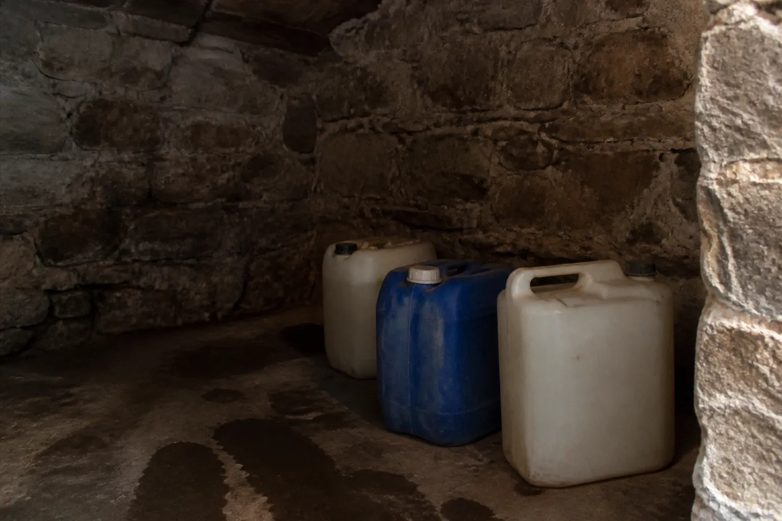 Bidons de produits de traitement posés dans une cave humide