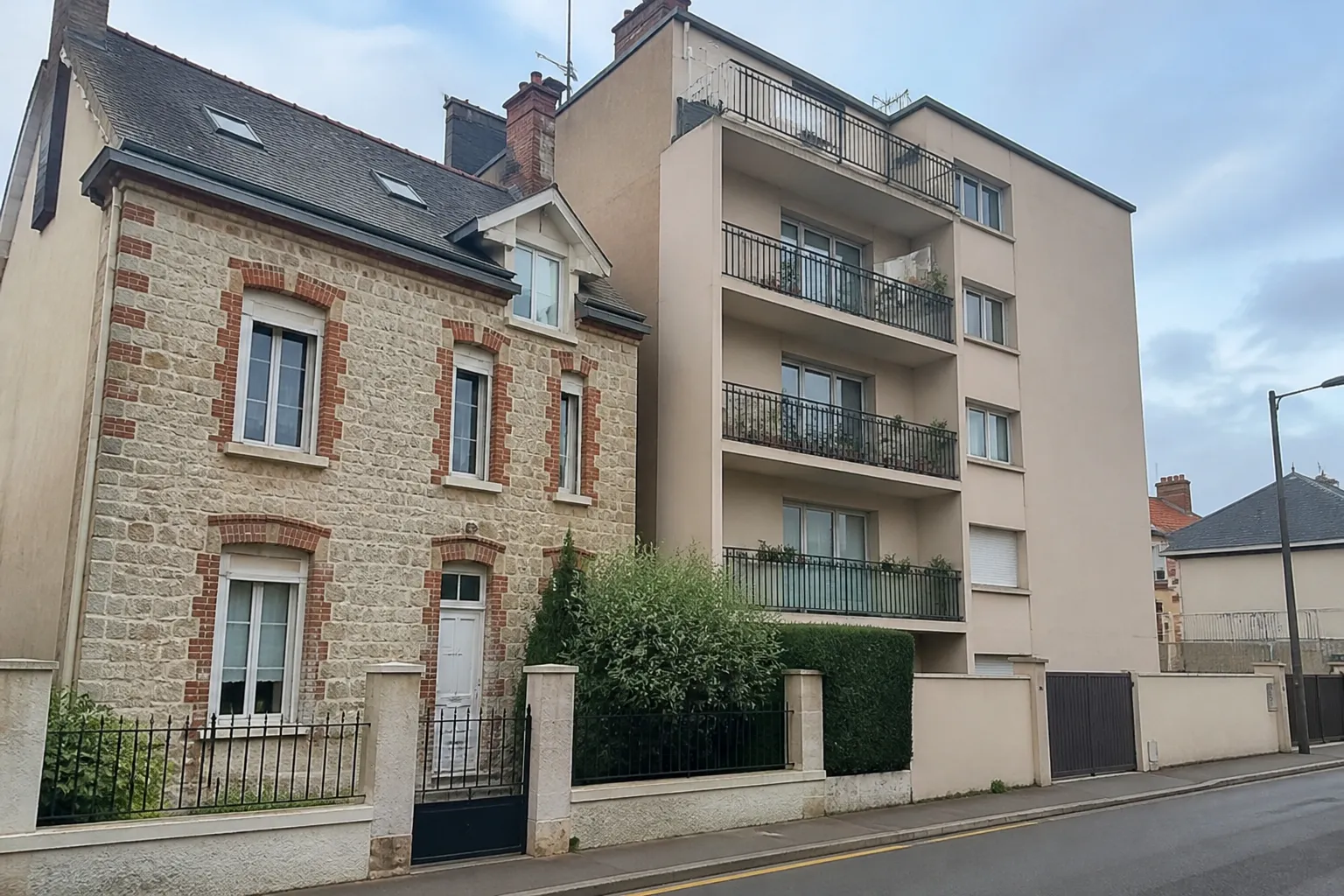 Maison individuelle et petit immeuble résidentiel côte à côte dans une ville
