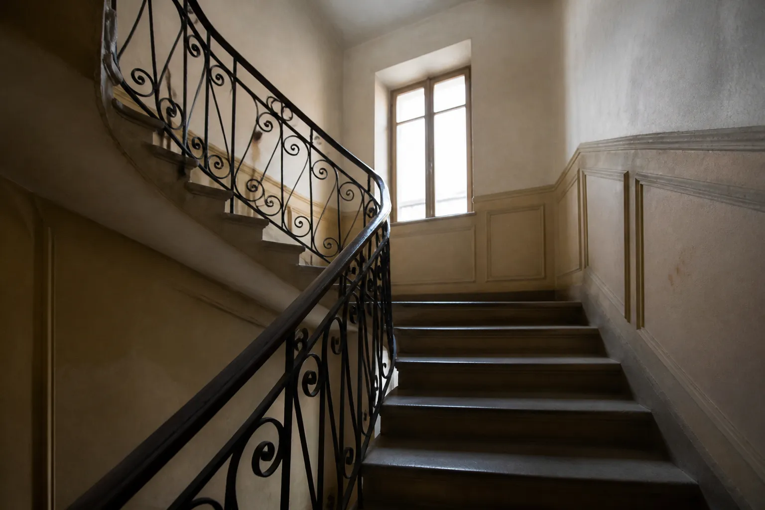 Cage d’escalier d’un immeuble ancien avec murs et rampe