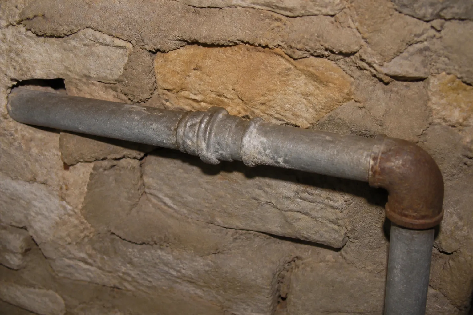 Ancienne canalisation en plomb grise dans une cave