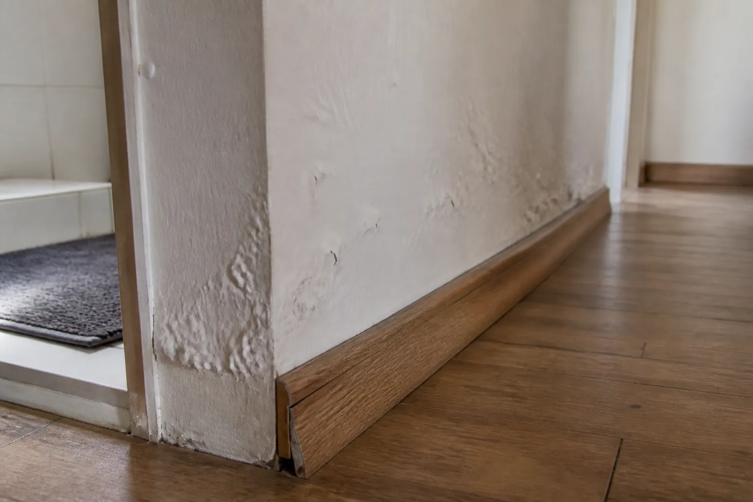Plinthe gonflée et peinture cloquée derrière une salle de bains