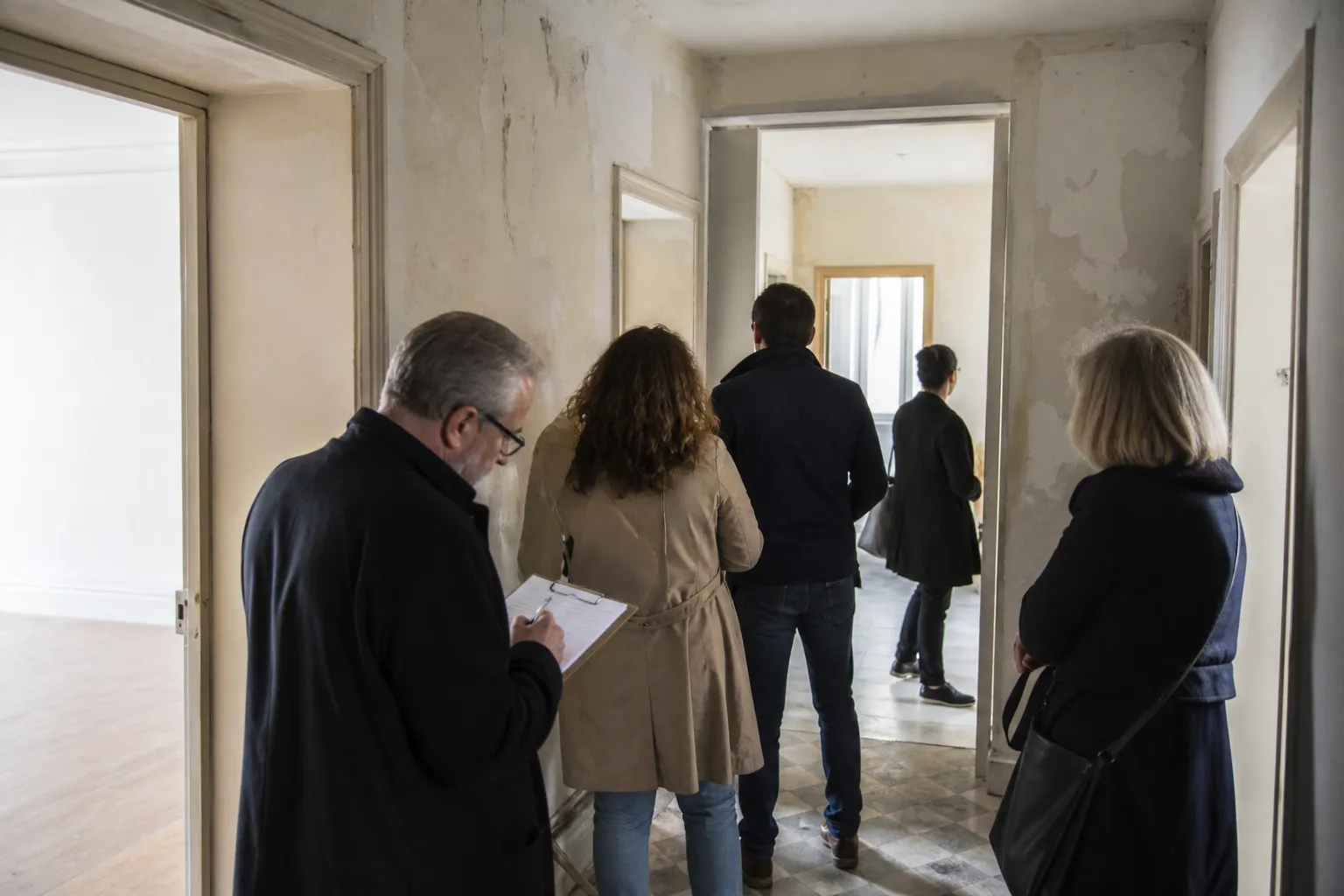 Petit groupe de visiteurs parcourant rapidement une maison lors d’une visite collective organisée