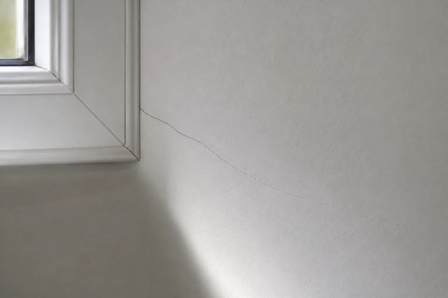 Mur intérieur fraîchement repeint présentant une fissure réapparue