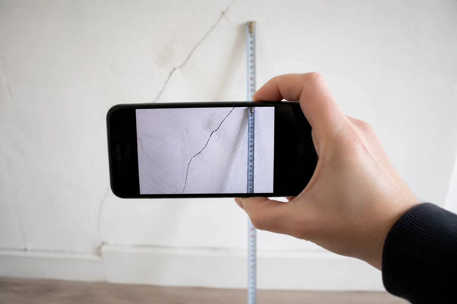 Smartphone photographiant une fissure avec un mètre ruban comme repère